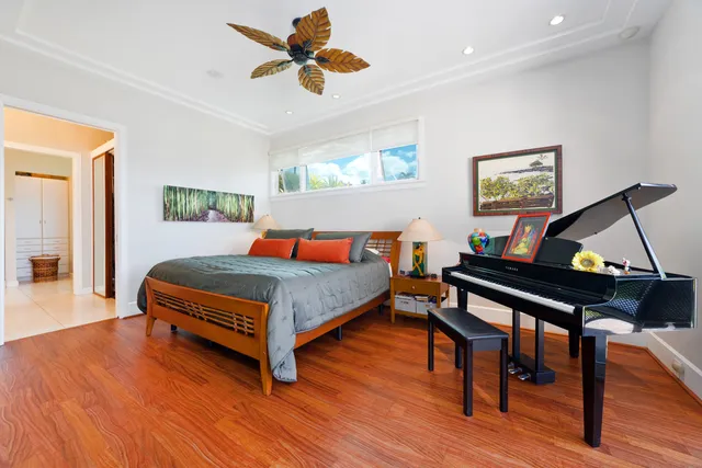 a bedroom with a bed a dresser and wooden floor