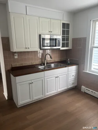 a kitchen with stainless steel appliances granite countertop a stove a sink and white cabinets