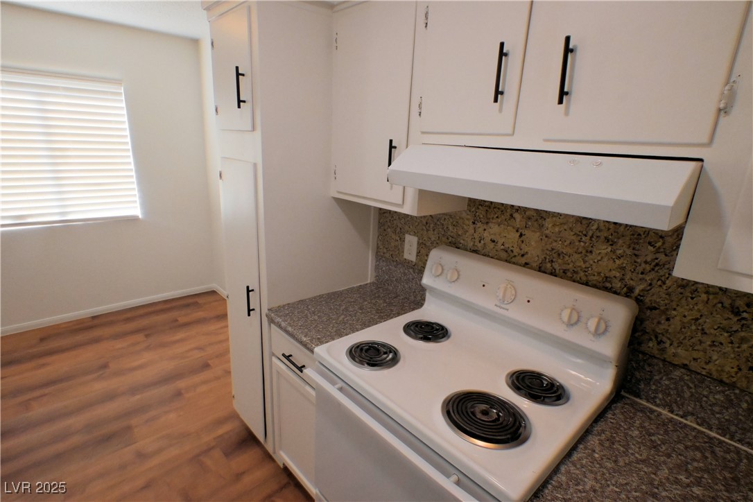 2608 East Mesquite Avenue, Unit 3 Las Vegas, NV 89101 - Photo 6 of 16 Kitchen featuring white range with electric cooktop, dark countertops, range hood, white cabinets, and dark wood-style flooring