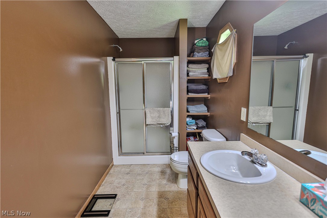 11154 Johnsford Road Southwest Beach City, OH 44608 - Photo 32 of 50 Bathroom featuring a shower with frosted sliding glass doors, a vanity with an integrated sink and laminate countertop, and built-in shelving