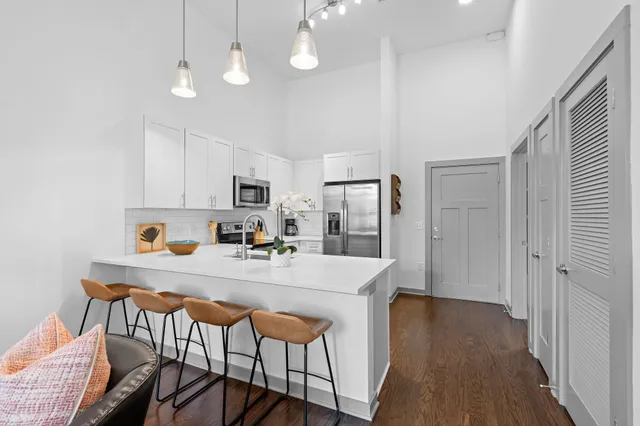 a kitchen with stainless steel appliances kitchen island granite countertop a refrigerator a stove a sink dishwasher and white cabinets with wooden floor