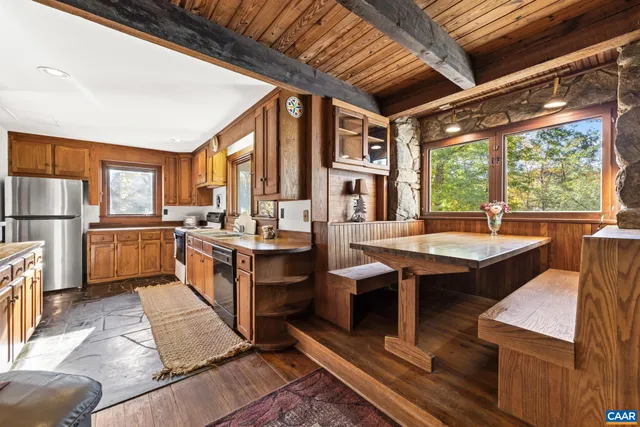 a kitchen with stainless steel appliances granite countertop a refrigerator a sink dishwasher a stove and white countertops with wooden floor