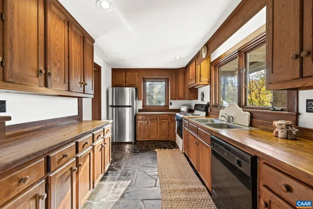 a kitchen with stainless steel appliances granite countertop a refrigerator a stove and a sink with wooden cabinets