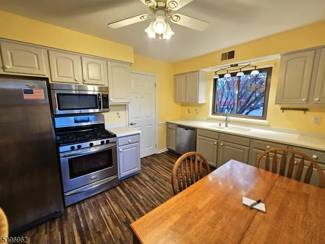 a kitchen with stainless steel appliances a stove a sink dishwasher and cabinets with wooden floor