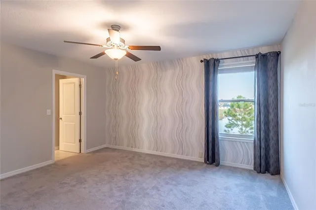 an empty room with windows and fan