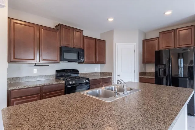 a kitchen with granite countertop a sink a stove and cabinets