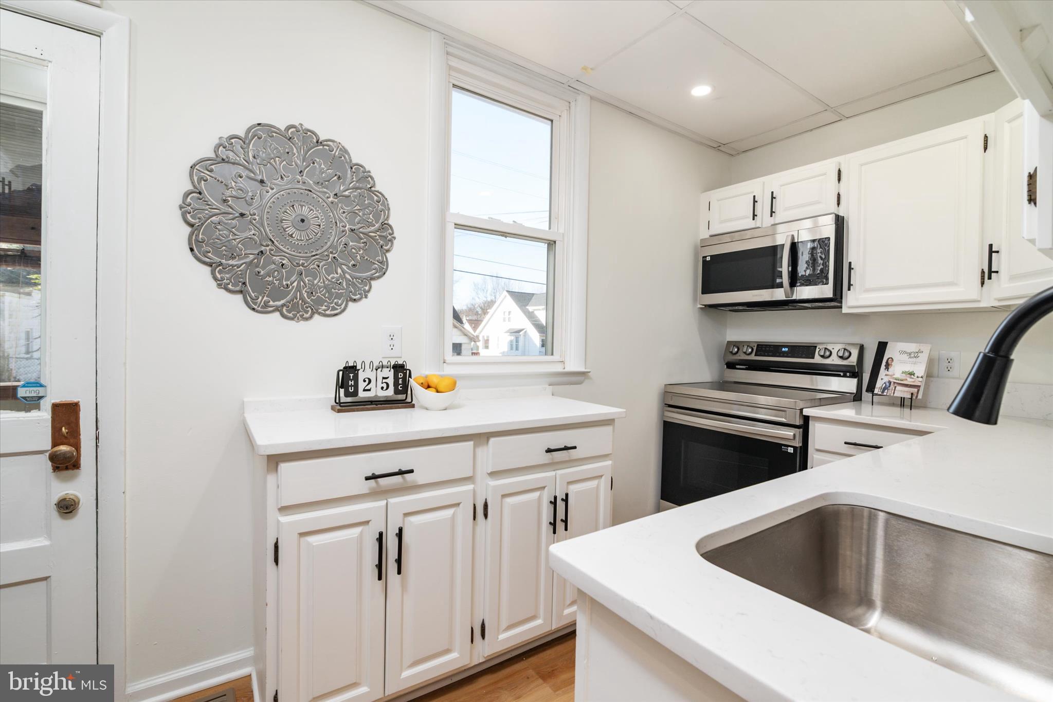 3827 Echodale Avenue Baltimore, MD 21206 - Photo 14 of 36 a kitchen with stainless steel appliances a sink a stove and microwave