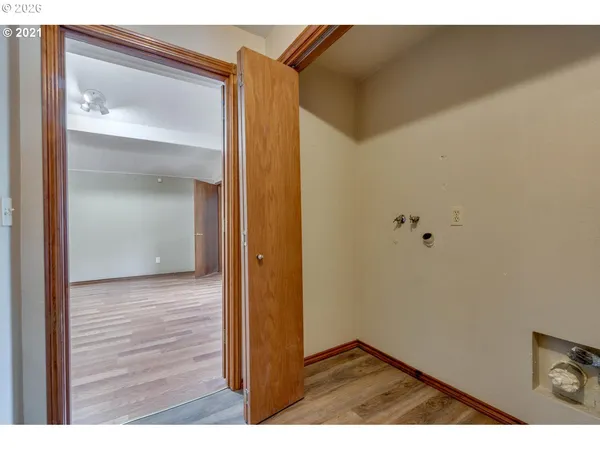 a view of an empty room with wooden floor and windows
