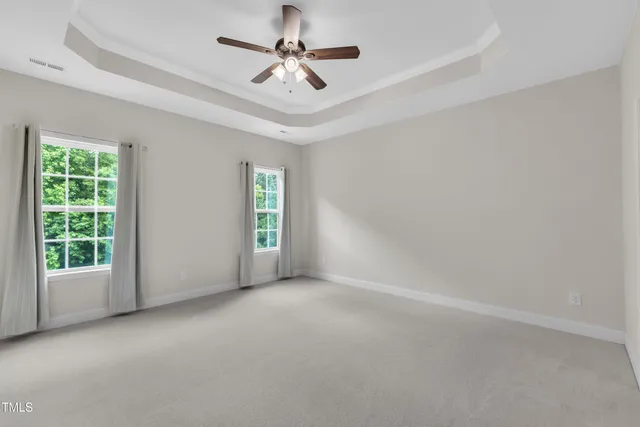 an empty room with windows and ceiling fan