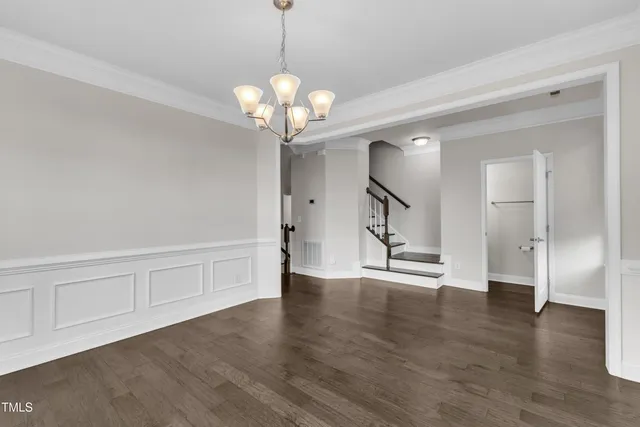 a view of an empty room with wooden floor and staircase