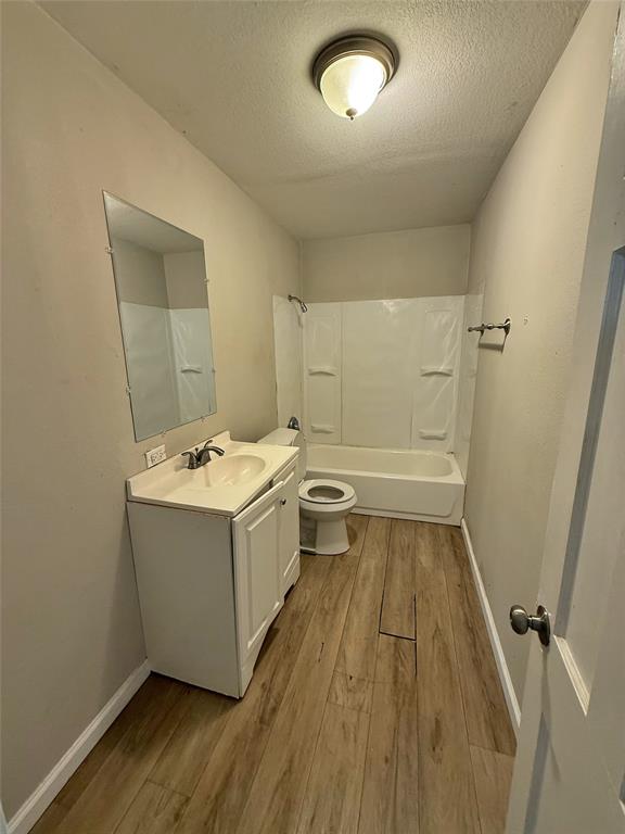 607 La Clede Street Bellmead, TX 76705 - Photo 4 of 7 Full bath featuring bathtub / shower combination, light wood finished floors, a textured ceiling, and vanity