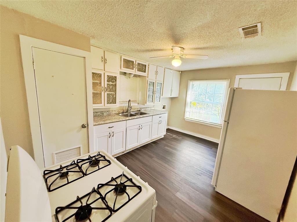 607 La Clede Street Bellmead, TX 76705 - Photo 5 of 7 Kitchen featuring white appliances, white cabinetry, glass insert cabinets, light countertops, and a ceiling fan
