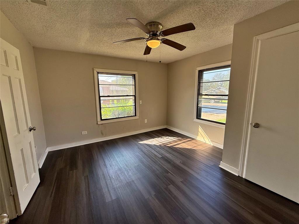 607 La Clede Street Bellmead, TX 76705 - Photo 6 of 7 Unfurnished bedroom with dark wood-type flooring, a ceiling fan, and a textured ceiling