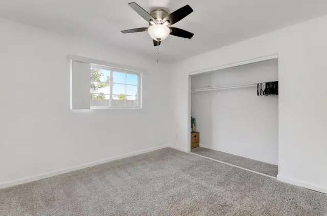 a view of an empty room with a ceiling fan and a window