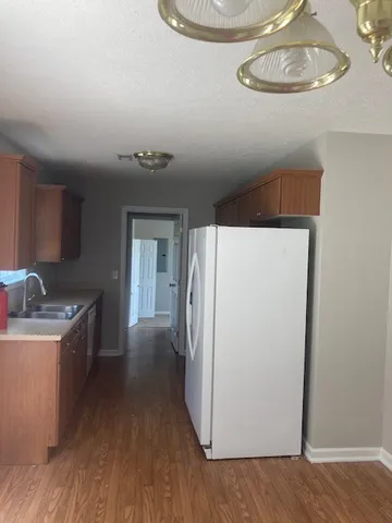 a kitchen with a refrigerator a stove and wooden floor