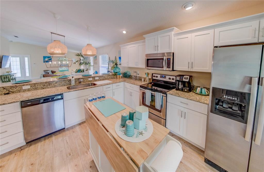 27 Mala Compra Road Palm Coast, FL 32137 - Photo 23 of 57 a kitchen with stainless steel appliances granite countertop a refrigerator a stove a sink dishwasher and white cabinets with wooden floor