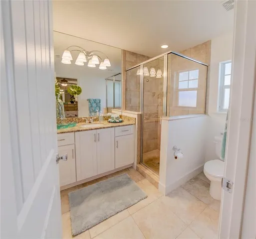 a spacious bathroom with a granite countertop sink a toilet and a shower