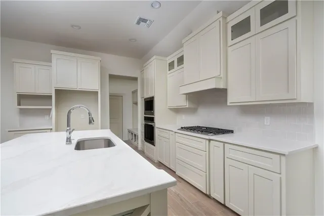 a kitchen with granite countertop a sink a stove and cabinets
