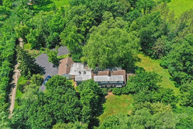 an aerial view of residential house with outdoor space and trees all around