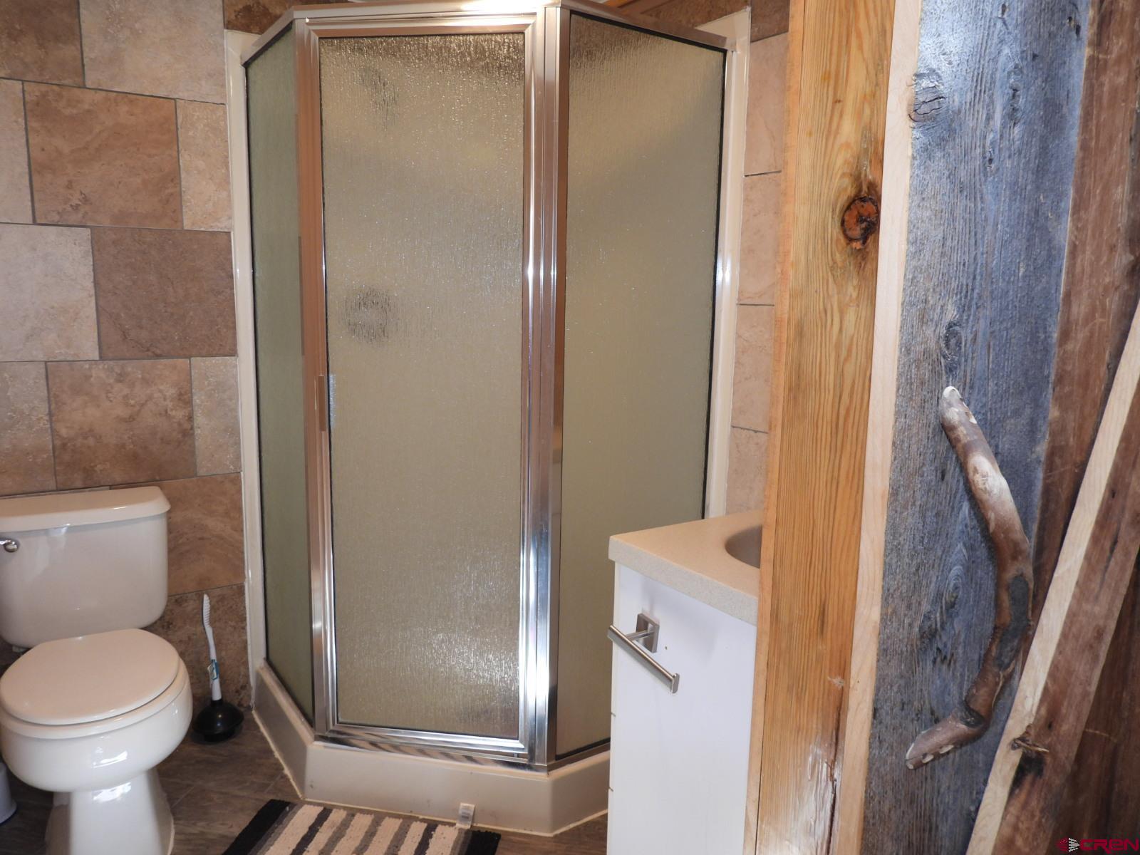 21764 R Road Cedaredge, CO 81413 - Photo 16 of 27 a bathroom with a granite countertop toilet and a shower