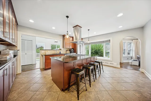 a dining hall with stainless steel appliances granite countertop a stove oven a sink a dining table and chairs with wooden floor