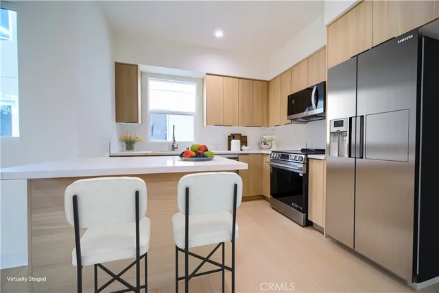 a kitchen with stainless steel appliances granite countertop a refrigerator a sink a stove a microwave a dining table and chairs with white cabinets