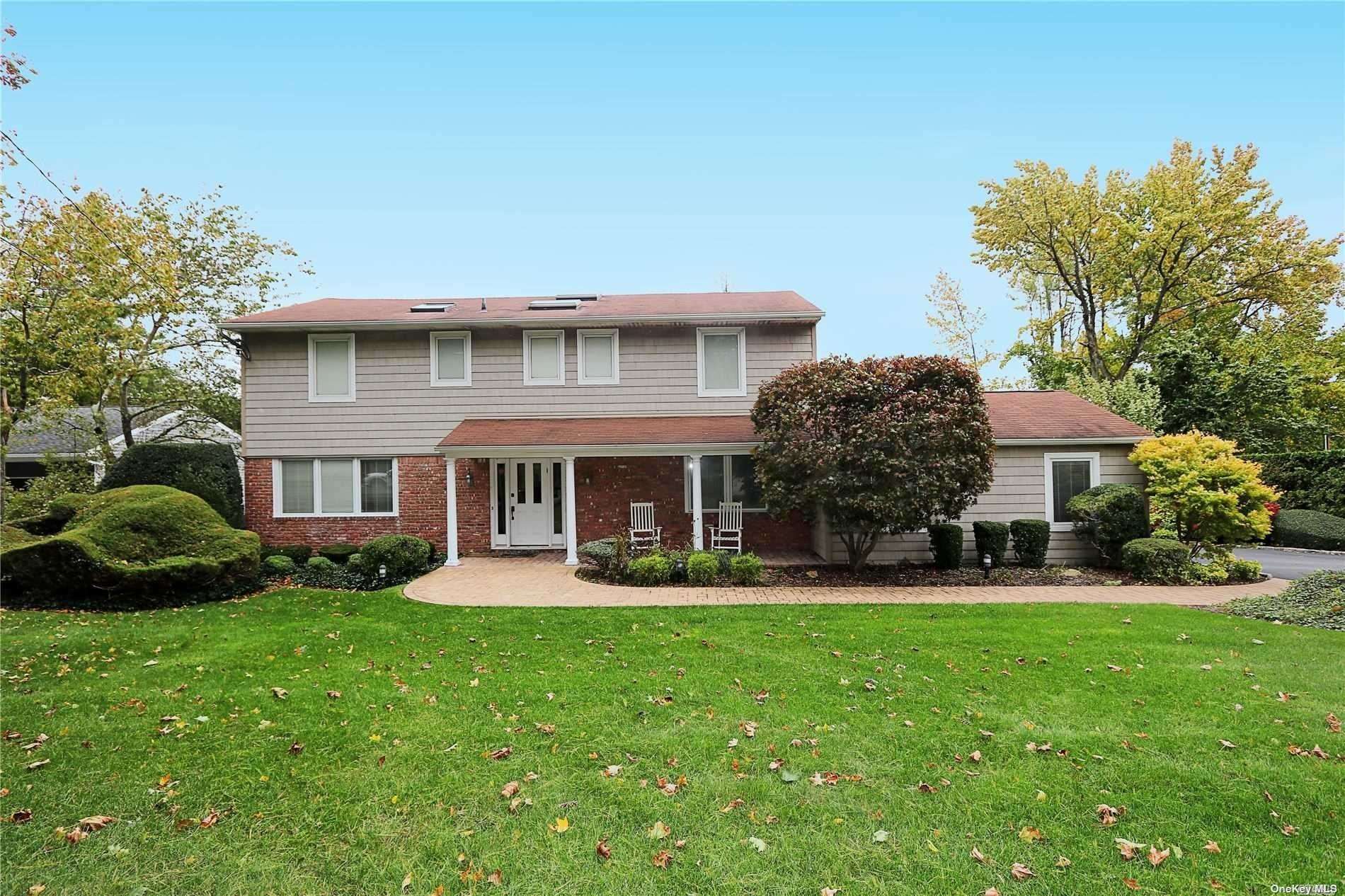 a front view of a house with a garden and trees