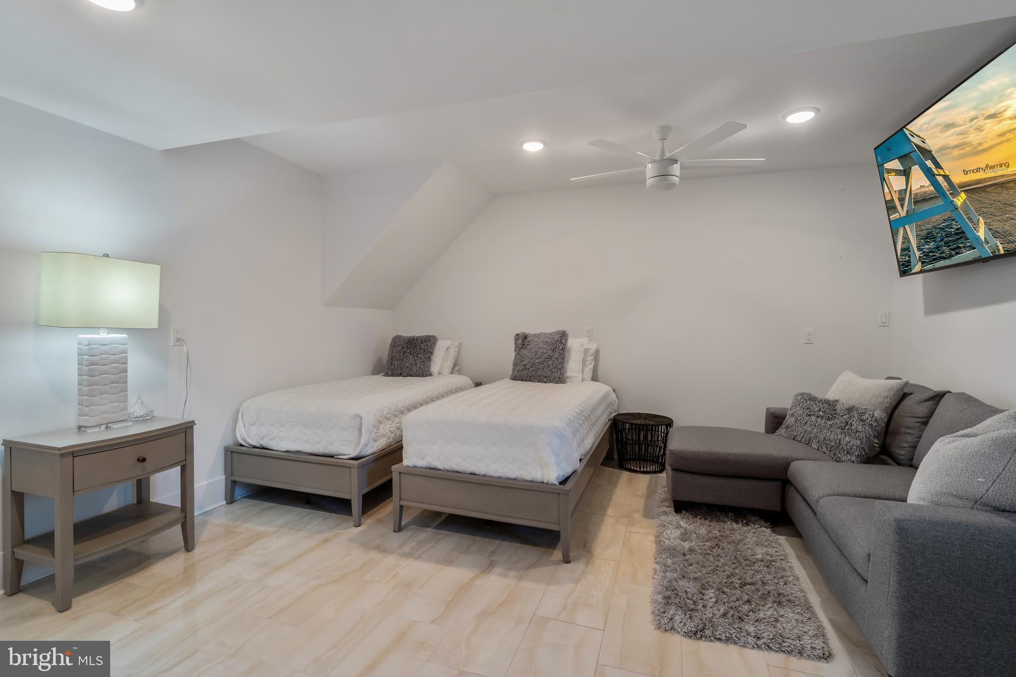 901 South Commonwealth Avenue, Unit SOUTH Strathmere, NJ 08248 - Photo 53 of 66 a spacious bedroom with a bed a couch and a lamp on table