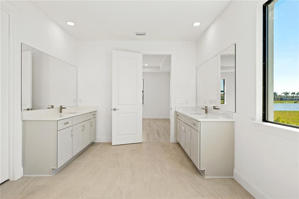 5830 Freestone Circle Apollo Beach, FL 33572 - Photo 20 of 34 a large white bathroom with a double vanity sink a mirror and a bathtub