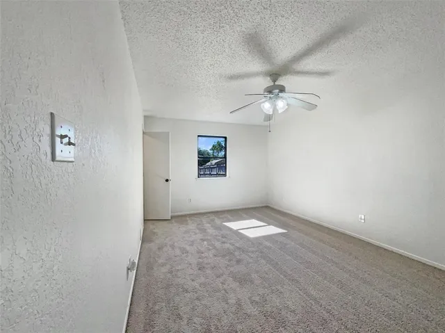 an empty room with a window and a ceiling fan