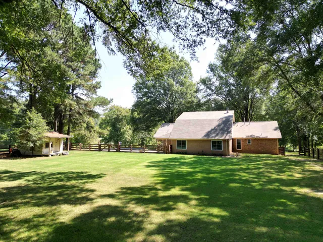 a view of a house with a big yard and large trees