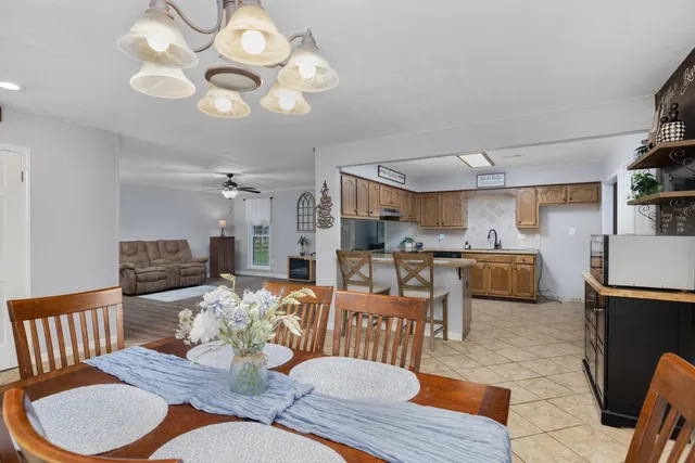a living room with lots of furniture kitchen view and a chandelier