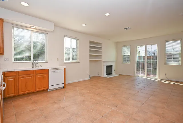 a view of an empty room with a window and a kitchen