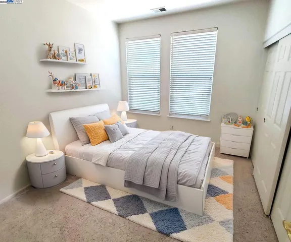 a bedroom with a bed and a dresser next to a window