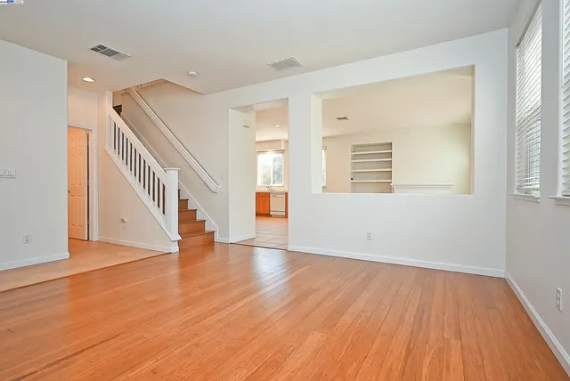 a view of an empty room with wooden floor and a window