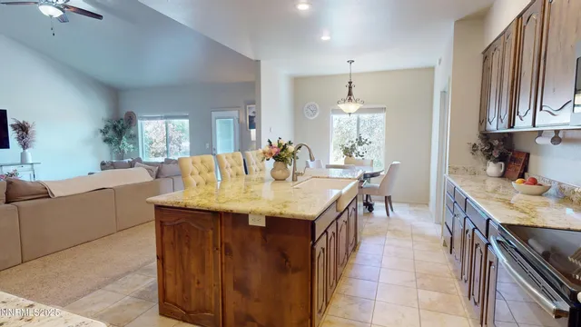 a dining hall with stainless steel appliances granite countertop a sink a stove a dining table and chairs