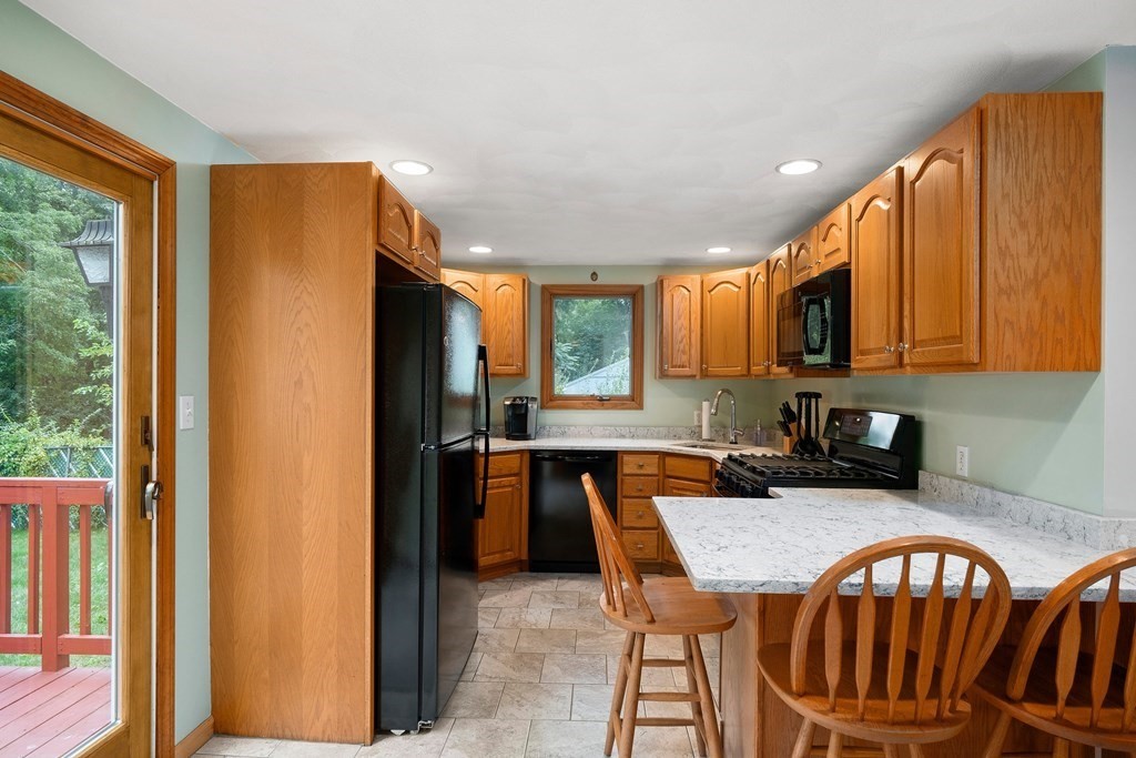 102 Orange Street Reading, MA 01867 - Photo 8 of 23 a kitchen with stainless steel appliances granite countertop a refrigerator a stove a sink a dining table and chairs with wooden floor