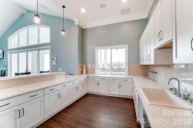 a large white kitchen with a large window a sink stainless steel appliances and cabinets