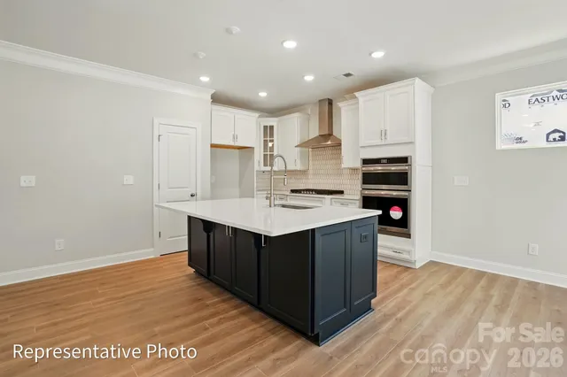 a kitchen with kitchen island a sink wooden floor and white stainless steel appliances