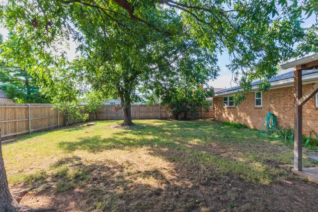 a view of a yard with a house and a large tree