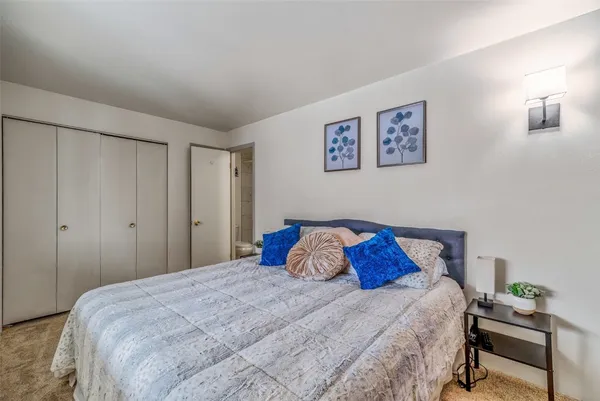 a bedroom with a bed and a lamp on dresser