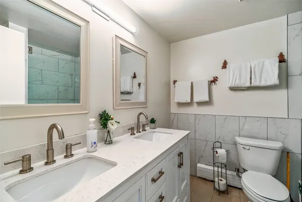 a bathroom with a granite countertop toilet sink and mirror