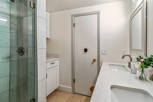 a bathroom with a granite countertop sink a mirror and shower