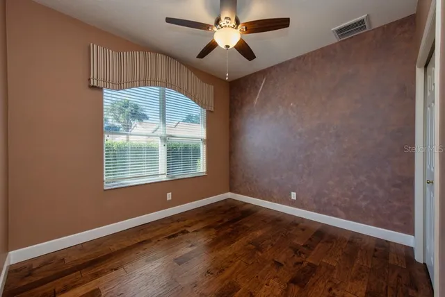 a view of empty room with wooden floor and fan