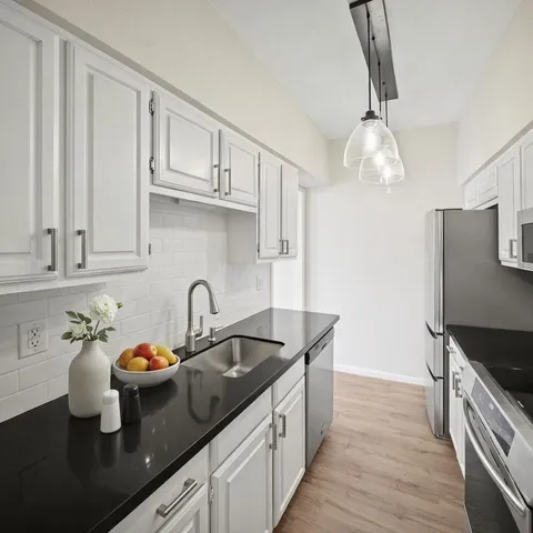 a kitchen with granite countertop a sink stainless steel appliances and cabinets