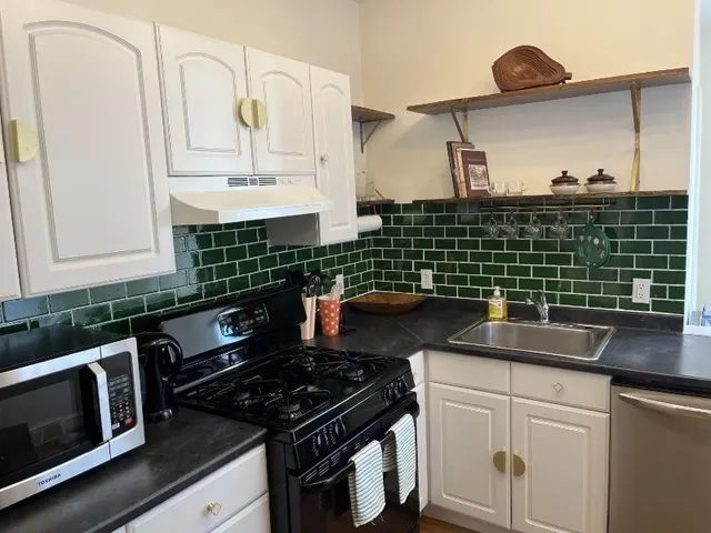 a kitchen with granite countertop a sink stove and cabinets