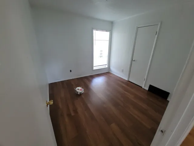 an empty room with wooden floor and window