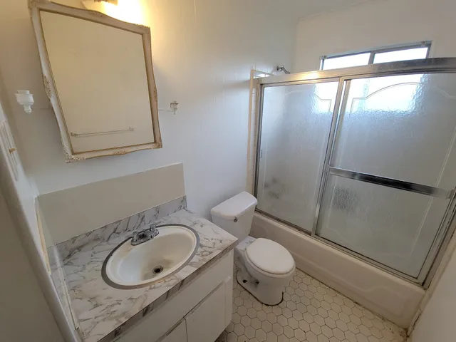 a bathroom with a granite countertop sink toilet and shower