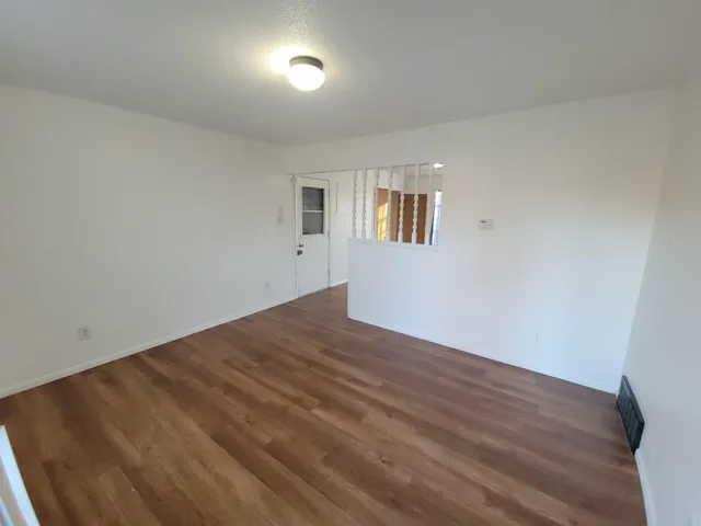 a view of empty room with wooden floor and fan