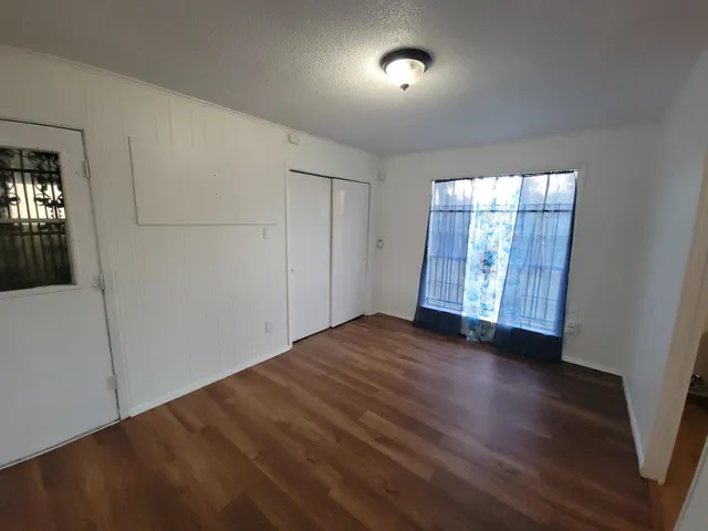 an empty room with wooden floor and windows
